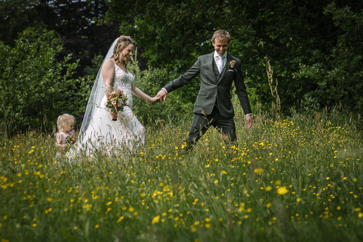 Bruidspaar lopend hand_in_hand groen gras landgoed_wolfslaar Breda trouwfoto natuurlijke authentieke trouwreportage documentair bruidsfotograaf