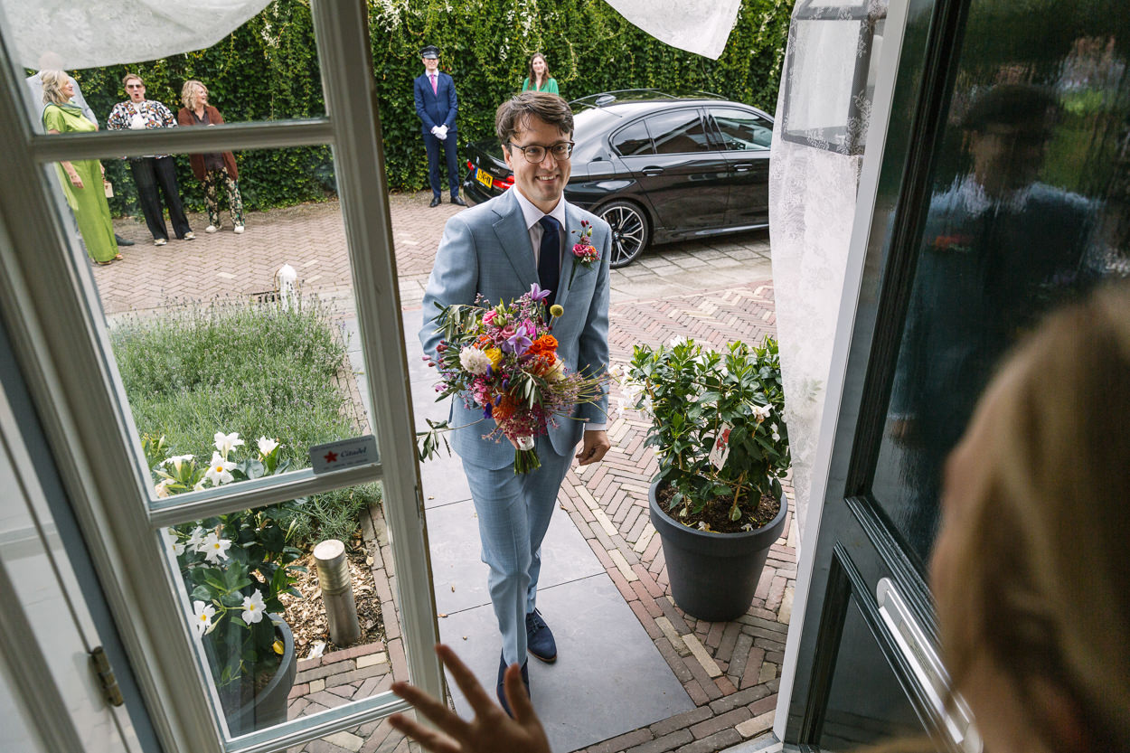 ophaalmoment bruidegom voordeur ongedwongen bruidsfotografie natuurlijke spontane trouwfoto documentair trouwfotograaf bruidsfotograaf breda rijk_van_de_keizer amsterdam