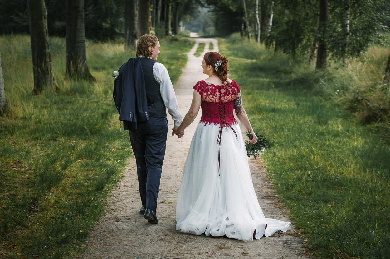 bruidspaar loopt samen weg van camera tijdens fotoshoot mastbos natuurlijke bruidsfotografie ongedwongen relaxte bruidsfoto door journalistiek trouwfotograaf documentair bruidsfotograaf Breda